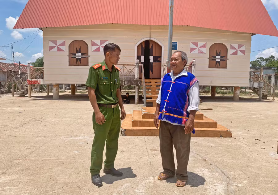 Ông Đinh Văn Chiêm trao đổi thông tin với cán bộ Công an xã Yang Nam, huyện Kông Chro. Ảnh: R’Ô HOK