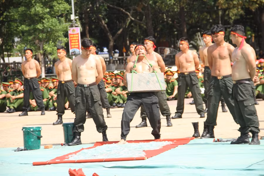 Một chiến sĩ biểu diễn vận khí công, dùng răng mang vật nặng đi trên mảnh chai thủy tinh. Ảnh: Hoàng Bình Một chiến sĩ biểu diễn vận khí công, dùng răng mang vật nặng đi trên mảnh chai thủy tinh. Ảnh: Hoàng Bình