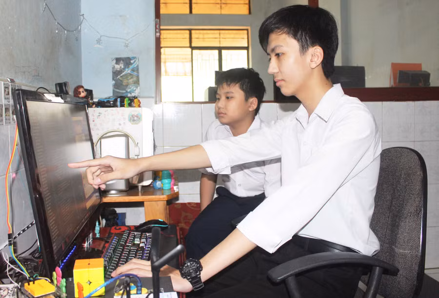 Em Trần Đăng Khoa (bìa phải) chia sẻ với em trai về lập trình “Ứng dụng học ngôn ngữ và hỗ trợ giao tiếp cho người câm/điếc”. Ảnh: Phan Lài