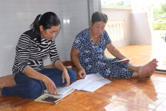 Ngày nào cũng vậy, chị Huyền (trái) cứ đem sách vở của Hùng và Uyên ra xem để đỡ nhớ - Ảnh: Phúc Nguyên