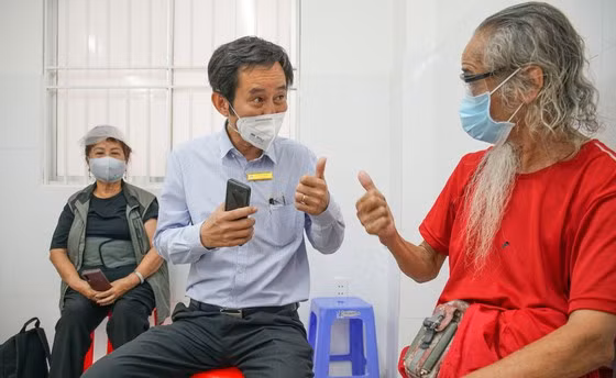 BS-CKII Trần Văn Khanh - Giám độc Bệnh viện Lê Văn Thịnh trò chuyện, hỏi thăm bác Lê Thăng (72 tuổi) khi bác tiêm ngừa vaccine phòng Covid-19 dành cho người lớn tuổi tại Bệnh viện Lê Văn Thịnh - TP Thủ Đức. Ảnh: Hoàng Hùng 