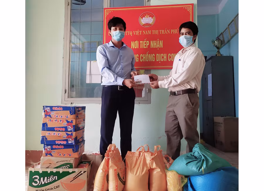 Anh Lê Đình Dinh (bìa trái) trao tiền ủng hộ phòng-chống dịch Covid-19 cho đại diện Ủy ban MTTQ Việt Nam thị trấn Phú Túc (huyện Krông Pa). Ảnh: Phan Lài