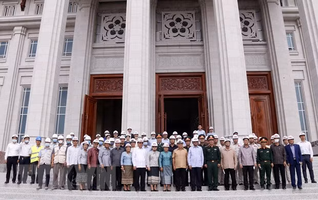 Tổng Bí thư, Thủ tướng Lào Thongloun Sisoulith cùng các quan chức Lào cùng cán bộ chiến sỹ Binh đoàn 11 trước tiền sảnh Tòa nhà Quốc hội mới của Lào. (Ảnh: Phạm Kiên/TTXVN)