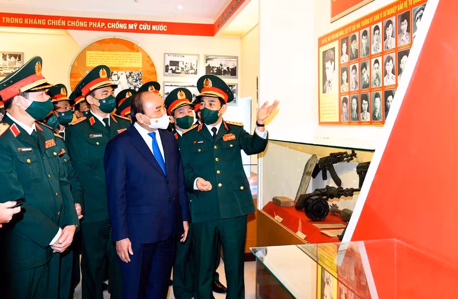 Đại tướng Phan Văn Giang, Ủy viên Bộ Chính trị, Bộ trưởng Bộ Quốc phòng (bìa phải) kể lại gương hy sinh của 22 liệt sĩ - học viên Trường Sĩ quan Chính trị, với Chủ tịch nước Nguyễn Xuân Phúc, trong ngày Chủ tịch nước về thăm và làm việc với Trường Sĩ quan Chính trị (ngày 19.12.2021). Ảnh: Tuấn Huy