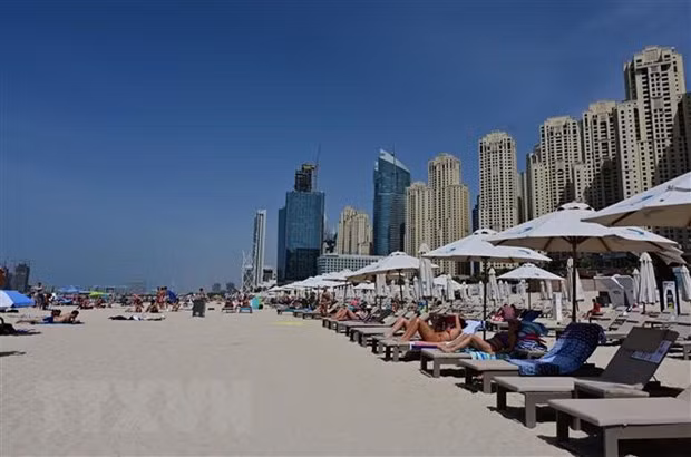 Khách du lịch tắm nắng trên bãi biển ở Dubai, UAE. Ảnh: AFP/TTXVN