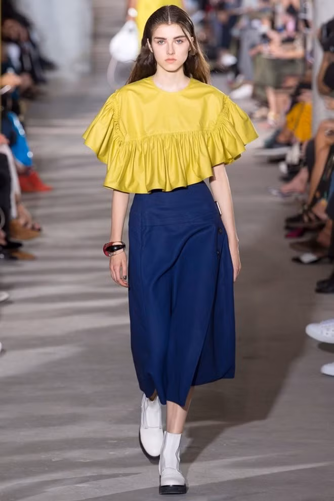  Phillip Lim giúp quý cô thời trang có thêm ý tưởng phối đồ khi ghép đôi crop top xếp bèo, mang gam vàng tươi sáng và quần ống rộng màu tối.