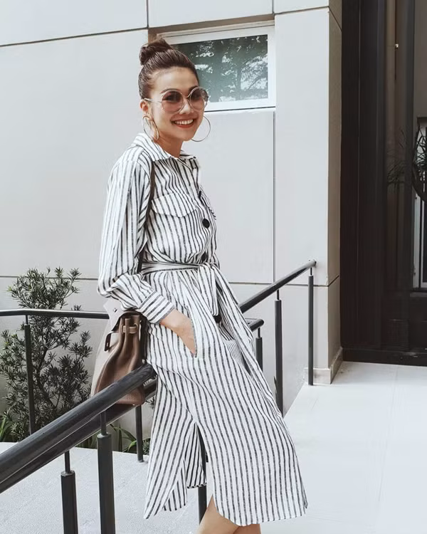 Khi chán các kiểu quần skinny khoe đôi chân dài, Thanh Hằng 'đổi gió' với phong cách nhẹ nhàng cùng thiết kế váy sơ mi kẻ sọc.