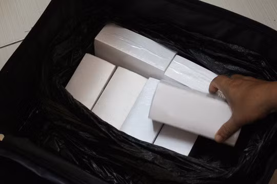 Va-li đựng 17 cọc giấy màu trắng mà các nghi phạm nói với nạn nhân là tiền USD nếu được rửa bằng hóa chất. Ảnh: Công an cung cấp