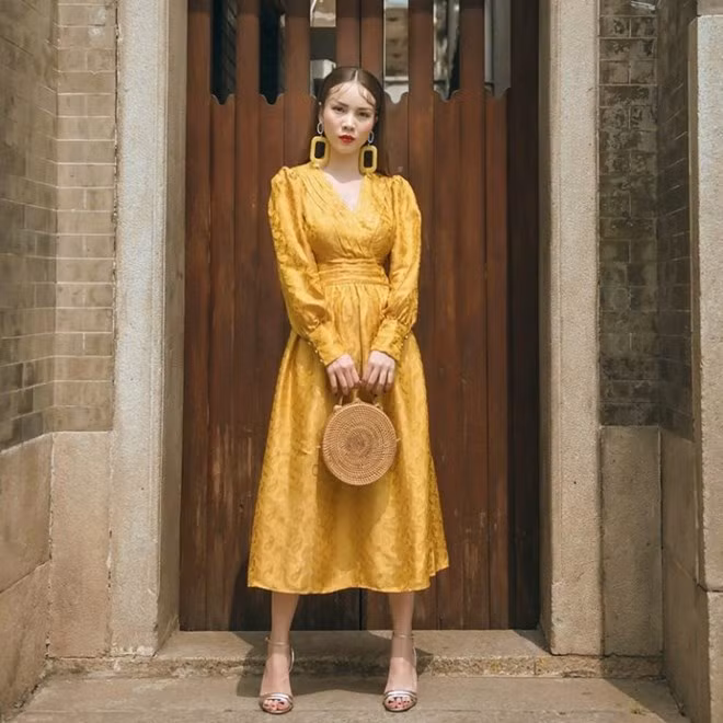  Yến Trang hóa quý cô cổ điển với bộ dầm thắt eo tay phồng, kết hợp cùng túi cói tròn xinh xắn.