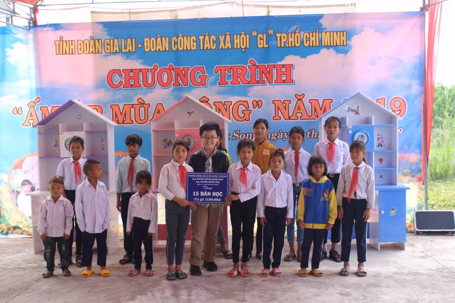 Em Nguyễn Huỳnh Nghị (hàng trước, thứ 5 từ trái qua)-con trai bác sĩ Nguyễn Tri Thức tặng bàn học cho các em học sinh ở xã Đak Song. Ảnh: Phan Lài