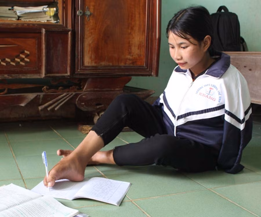 Không được may mắn như những người khác, Hlonh phải viết chữ bằng chân. Ảnh: P.L