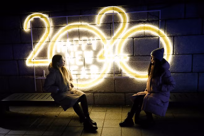  Hai cô gái chụp hình trước đèn chiếu sáng năm 2020 trong Đêm giao thừa ở Seoul, Hàn Quốc ngày 31.12 - Ảnh: Reuters