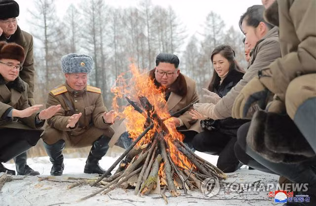 Ông Kim và phu nhân cùng các quan chức sưởi ấm. Ảnh: Yonhap