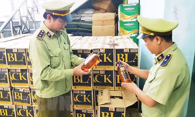 Lực lượng chức năng kiểm tra số rượu ngoại lậu vừa bắt giữ. (Ảnh: Võ Dung/TTXVN)