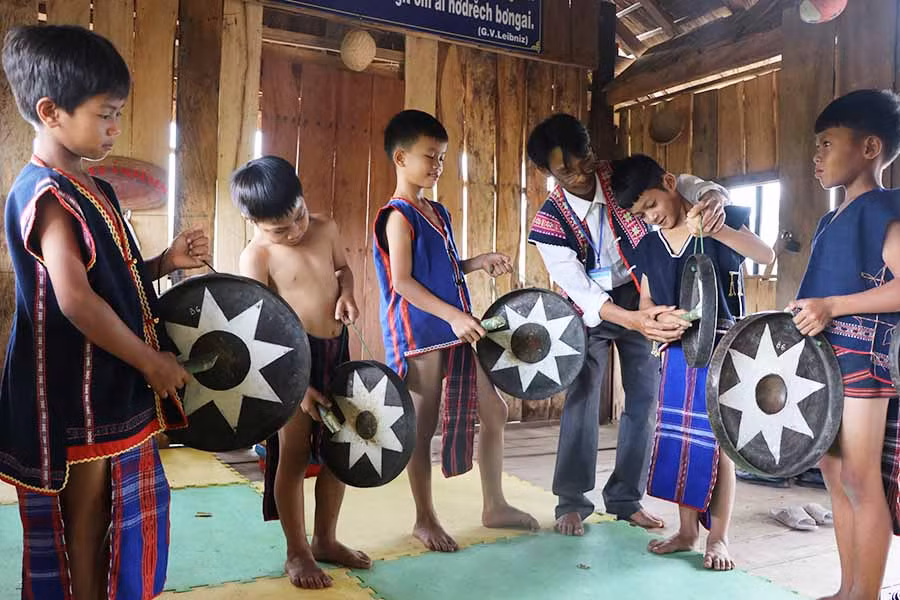  Thầy Đinh Văn Khoa (thứ 3 bên phải) hướng dẫn cách đánh cồng chiêng cho các em học sinh điểm trường 3 làng xã Tú An. Ảnh: N.M