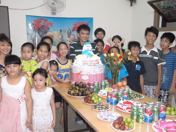 Trong bức ảnh chụp năm 2011 này, anh sinh viên tình nguyện Ben Hoàng Nguyễn đang mừng sinh nhật cùng các em nhỏ ở trại mồ côi Thủy Xuân và giải thích với các em một buổi sinh nhật được tổ chức như thế nào - Ảnh: NVCC