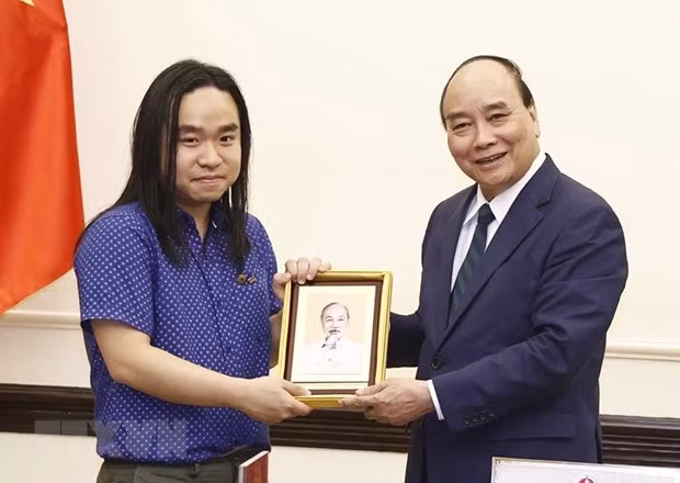 Chủ tịch nước Nguyễn Xuân Phúc tặng ảnh Chủ tịch Hồ Chí Minh cho dịch giả trẻ Nguyễn Bình. (Ảnh: Thống Nhất/TTXVN)