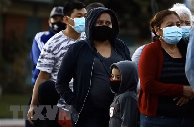 Người dân đeo khẩu trang phòng lây nhiễm COVID-19 khi xếp hàng chờ nhận hàng phân phát tại Los Angeles, California, Mỹ, ngày 19/11/2020. (Nguồn: THX/TTXVN)