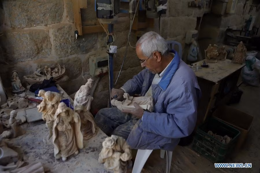  10 Một nhà điêu khắc người Palestine hoàn thiện tác phẩm điêu khắc bằng gỗ ô liu cho lễ Giáng sinh tại một xưởng ở thành phố Bethlehem, Bờ Tây. Ảnh: Xinhua