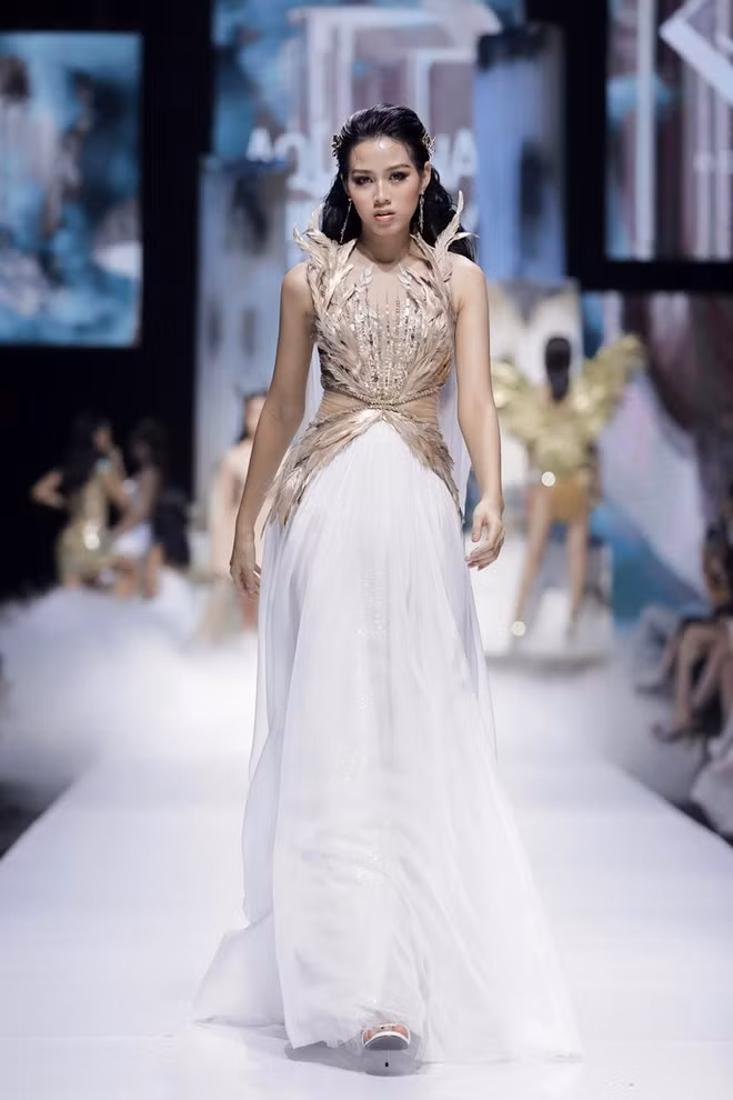 Đỗ Long mong muốn mang đến những gương mặt mới nhằm tạo hơi thở cho show diễn. Hoa hậu Đỗ Thị Hà nắm giữ vai trò first face. Dù chưa có nhiều kinh nghiệm sàn diễn, chân dài Thanh Hóa vẫn sải bước với thần thái đầy tự tin trong sự cổ vũ của các khách mời. Người đẹp sinh năm 2001 được nhà mốt lựa chọn thiết kế đính kết cầu kỳ, giúp cô khoe nhan sắc cuốn hút nhưng vẫn giữ được sự kín đáo nhất định ẢNH: KIẾNG CẬN
