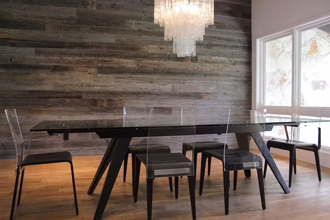 Phòng ăn hiện đại với bàn ăn bằng nhựa acrylic và bức tường gỗ tái chế.
