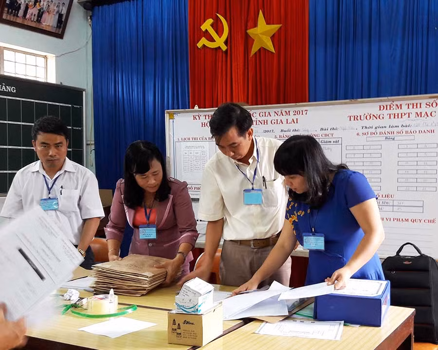 2 Cán bộ Điểm thi 08-Trường THPT Mạc Đĩnh Chi - đang niêm yết bài thi môn Ngữ Văn. Ảnh: Đinh Yến