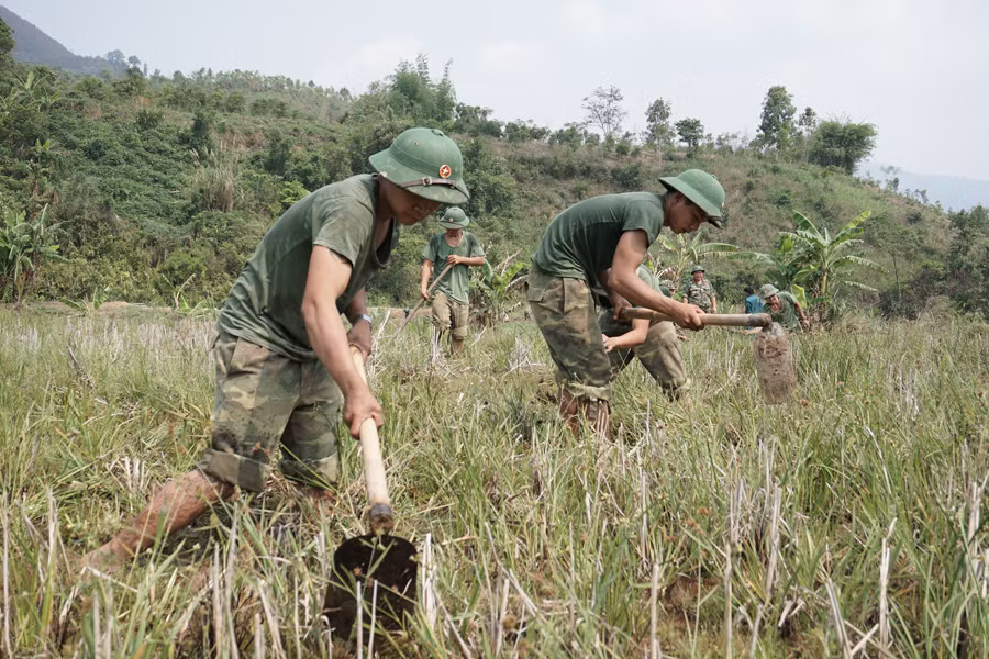Cán bộ chiến sĩ Trung đoàn 28 giúp dân khai hoang ruộng đồng. Ảnh: V.H