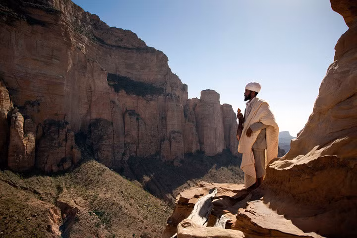 Một giáo sĩ đứng trên gờ một vách đá ở phía trước lối vào một nhà thờ Chính thống Ethiopia ở Megab, Ethiopia (châu Phi). Ảnh: Getty.