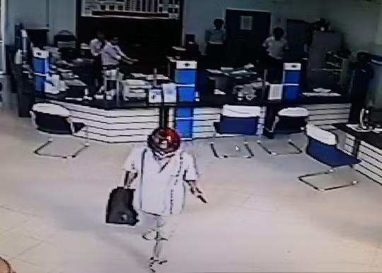 Sau khi cướp được tiền, kẻ cướp ung dung cầm súng bước ra ngoài tẩu thoát. Ảnh lấy ra từ camera an ninh Sau khi cướp được tiền, kẻ cướp ung dung cầm súng bước ra ngoài tẩu thoát. Ảnh lấy ra từ camera an ninh