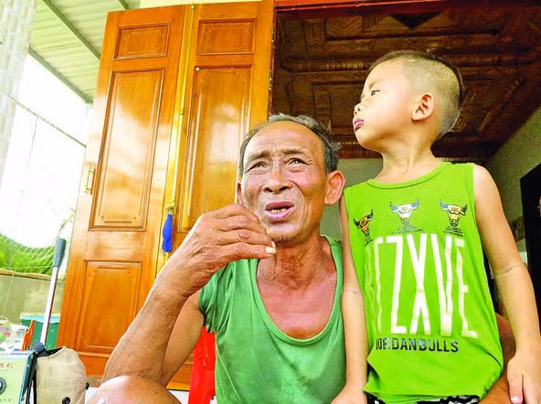 Ông Nguyễn Lạc cùng đứa cháu tại căn nhà của mình, nơi đêm trước đã cưu mang hàng chục người dân trú bão.