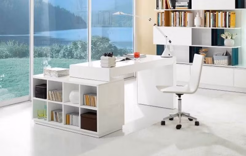 Kệ đựng sách và bàn làm việc màu trắng gắn liền nhau được đặt trong không gian làm việc thoáng mát, phía trước là cửa kính hướng ra ngoài có cảnh vật thiên nhiên. Kệ đựng sách và bàn làm việc màu trắng gắn liền nhau được đặt trong không gian làm việc thoáng mát, phía trước là cửa kính hướng ra ngoài có cảnh vật thiên nhiên.