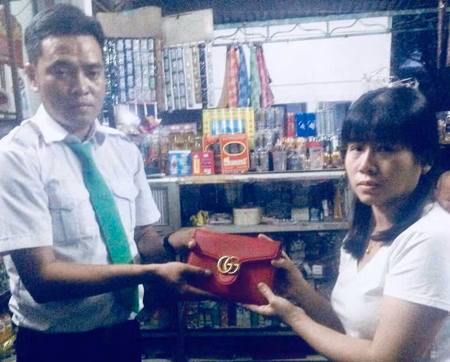 Tài xế Nguyễn Minh Vương trao lại chiếc túi xách cho người thân chủ nhân nhân chiếc túi bỏ quên. Ảnh: Lê Hoà.