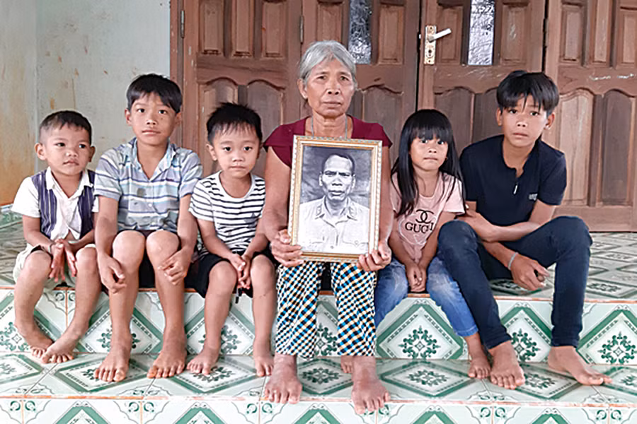 Bà Siu Pil (vợ ông A Sanh) và các cháu bên di ảnh người anh hùng. Ảnh: Nguyễn Quang Tuệ