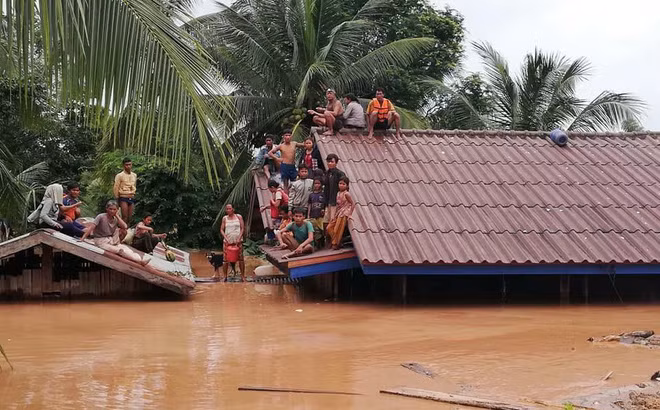 Nhiều nạn nhân phải leo lên mái nhà để tránh nước lũ do vỡ đập thủy điện Xepian-Xe Nam Noy. (nguồn internet) Nhiều nạn nhân phải leo lên mái nhà để tránh nước lũ do vỡ đập thủy điện Xepian-Xe Nam Noy.
