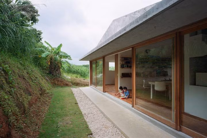  Mặt sau nhà thiết kế dựa vào lưng đồi, mái hiên rộng làm sân chơi cho những đứa trẻ.