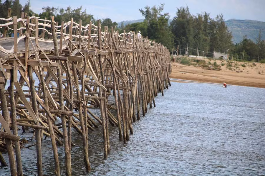 Mặt và trụ cầu được làm hoàn toàn từ ván gỗ, thành cầu nối với nhau bằng thân tre. 