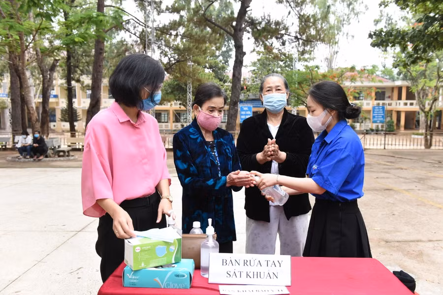 Đoàn viên thanh niên phường Hòa Lư hướng dẫn sát khuẩn trước khi vào nơi bỏ phiếu. Ảnh: Đức Thụy
