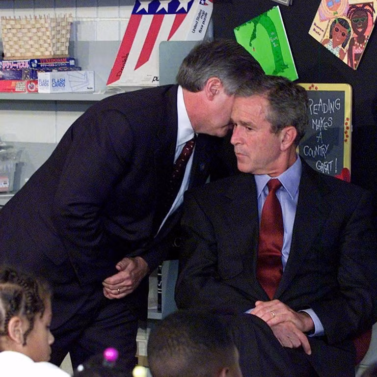 Cựu chánh văn phòng Nhà Trắng Andy Card thì thầm vào tai tổng thống khi đó, ông George W. Bush để cho ông biết về vụ máy bay đâm vào Trung tâm Thương mại Thế giới trong chuyến thăm Trường tiểu học Emma E. Booker ở Sarasota, Florida. (Ảnh: Doug Mills / AP)