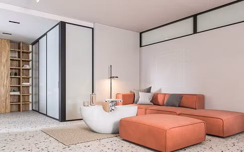 Bắt đầu bước vào căn hộ là phòng khách mở rộng rãi, một ghế sofa dài màu cam nổi bật giữa căn phòng.