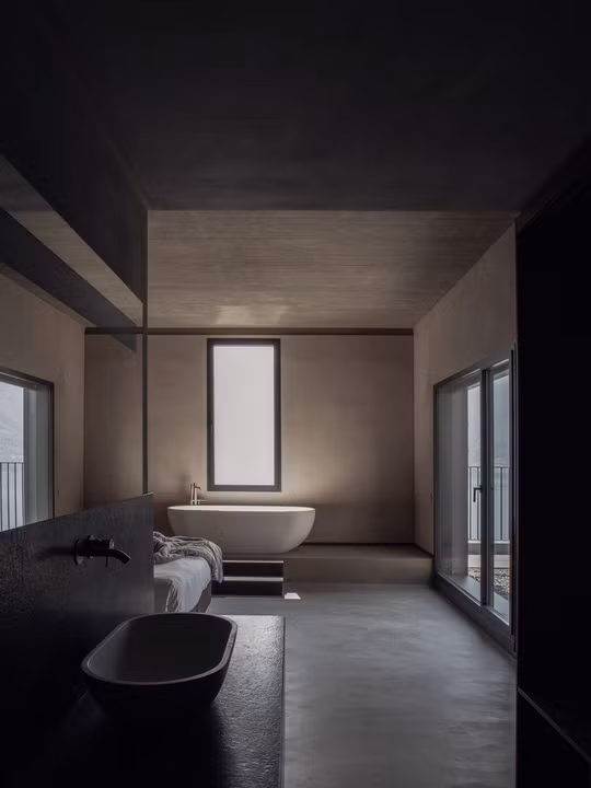 Với ngôi nhà ở Sala Comacina (Italy), văn phòng kiến trúc sư Lorenzo Guzzini chọn giải pháp phòng tắm mở, thông với phòng ngủ chính. Toàn bộ không gian được thiết kế với tông màu tối của đá serpentine, bê tông và thạch cao nhằm đem tới sự đối lập với thiên nhiên bên ngoài.