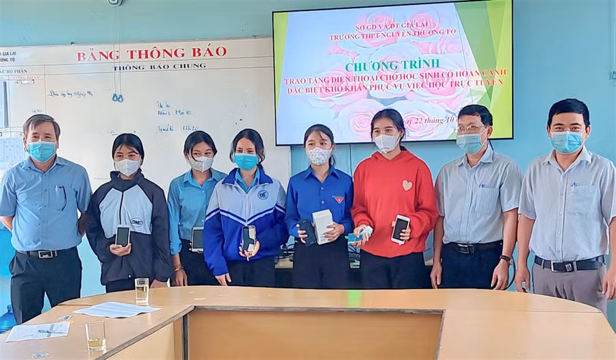 Em Rơmah H’Win (áo đỏ) cùng 4 học sinh có hoàn cảnh khó khăn của Trường THPT Nguyễn Trường Tộ (huyện Đức Cơ) phấn khởi nhận điện thoại do nhà trường trao tặng. Ảnh: Mộc Trà