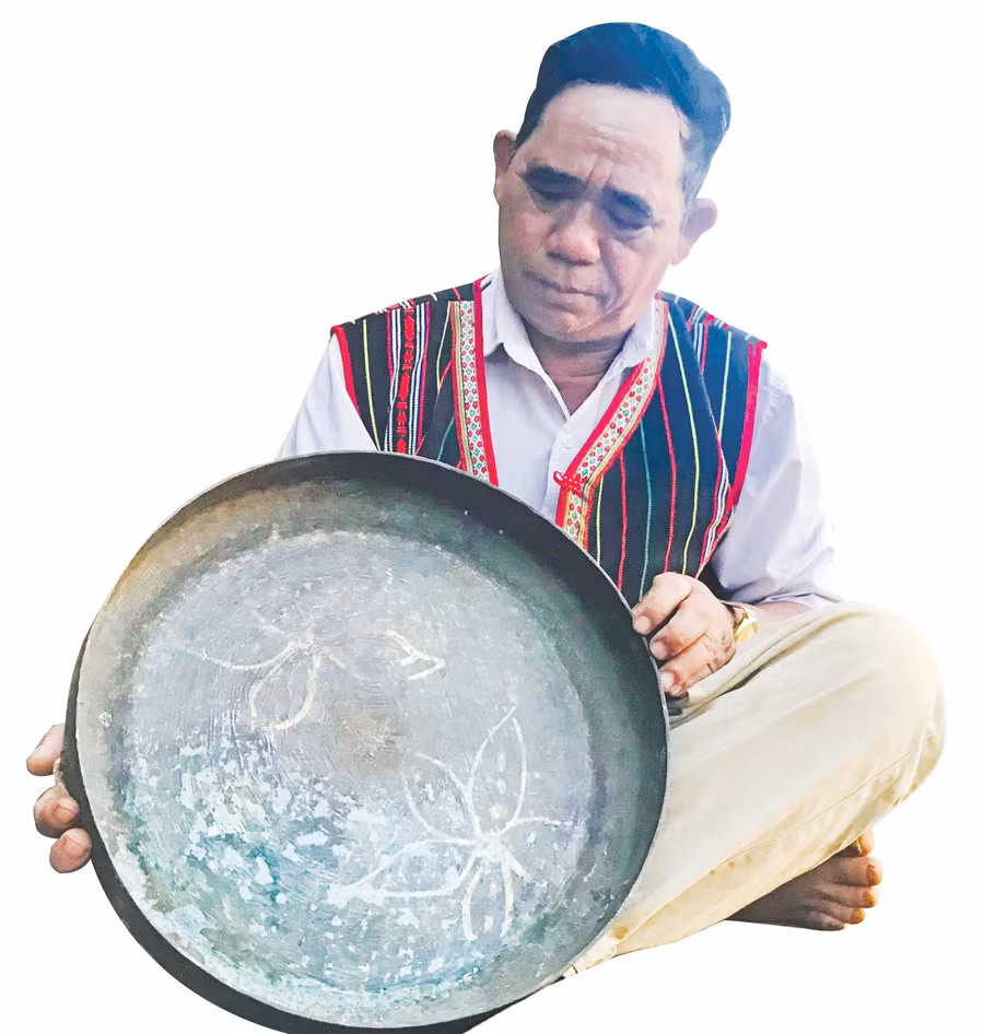 Nghệ nhân chỉnh chiêng Rơ Châm Luih bên chiếc chiêng Hronh Char. Ảnh: Trần Dung