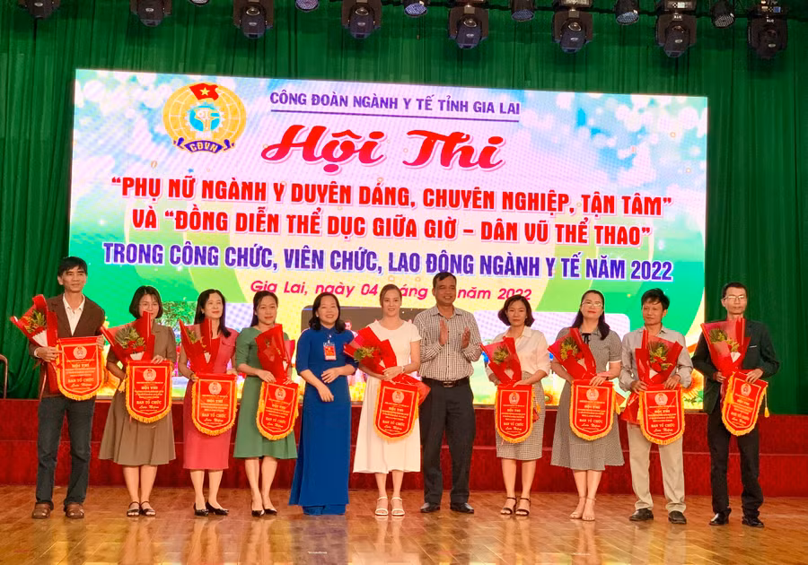Ông Đinh Hà Nam (thứ 5 từ phải qua)- Phó Giám đốc Sở Y tế tỉnh và bà Nguyễn Thị Ánh Xuân (thứ 5 từ trái qua)- Chủ tịch Công đoàn ngành Y tế Gia Lai trao hoa và cơ lưu niệm cho các đơn vị tham gia hội thi. Ảnh: Như Nguyện
