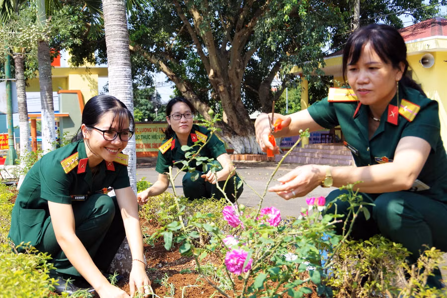 Thượng úy Quân nhân chuyên ngiệp Hà Thị Thu Huyền (bìa trái) đang cùng các chị, em trong đơn vị chăm sóc vườn hoa. Ảnh: Vĩnh Hoàng