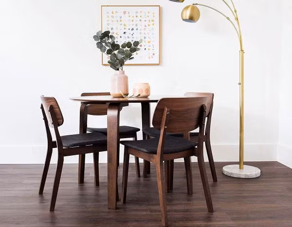 Một chiếc bàn tròn với chân gỗ uốn cong thanh lịch, cùng với bốn chiếc ghế đủ để cả gia đình có thể thưởng thức bữa tối ngay tại nhà.