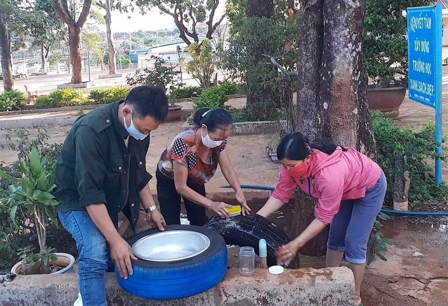 Các thầy cô giáo Trường Tiểu học Kim Đồng (huyện Đức Cơ) đang rửa lốp xe để chuẩn bị triển khai mô hình bồn rửa tay cho học sinh. Ảnh: Hồng Thi