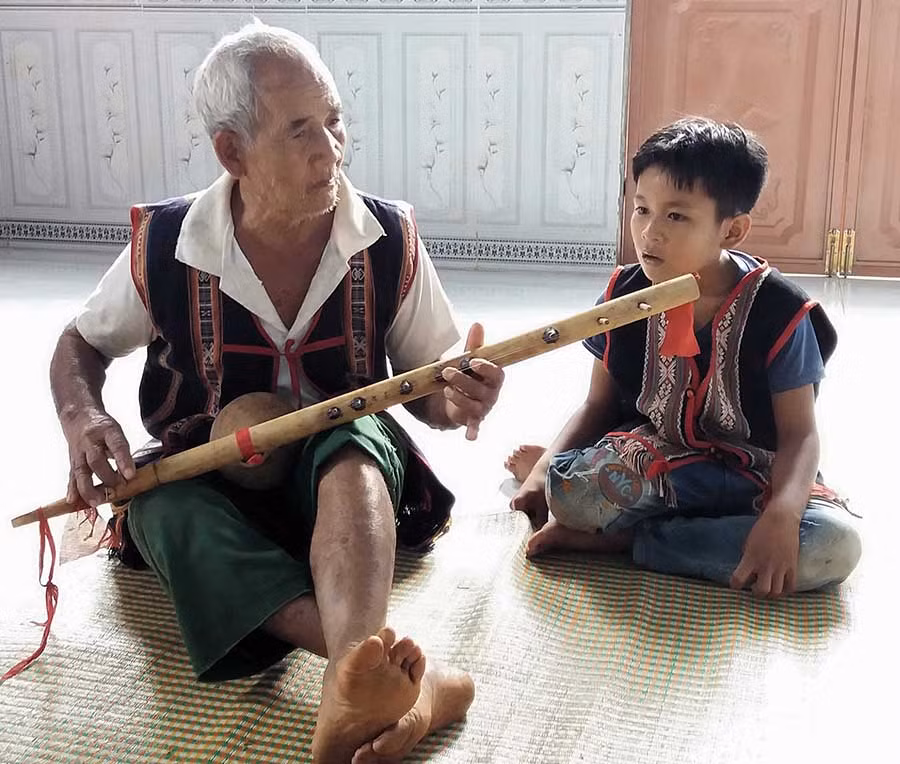  Già Rơ Châm Nha đàn cho cháu Tứ hát. Ảnh: N.N