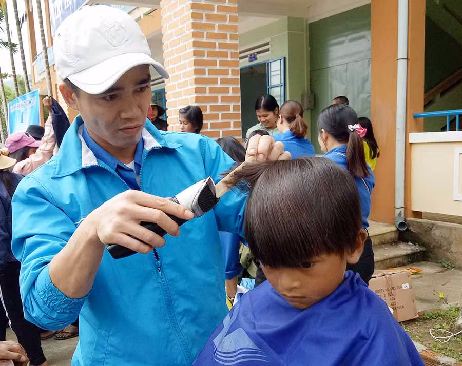  Một thành viên trong đoàn cắt tóc cho các em học sinh. Ảnh: P.L