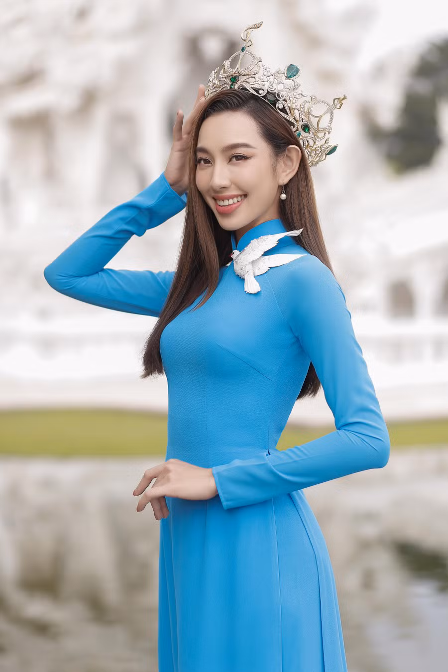 Thay vì chọn một mẫu thiết kế có màu sắc nổi bật và nhiều chi tiết, tân Hoa hậu Hòa bình Quốc tế 2021 quyết định diện một chiếc áo dài màu sắc nhẹ nhàng, có điểm nhấn là một chú bồ câu trắng đính trên cổ áo. Họa tiết này là ẩn ý về một thông điệp hòa bình mà Thùy Tiên muốn gửi gắm đến mọi người. Ảnh: NVCC