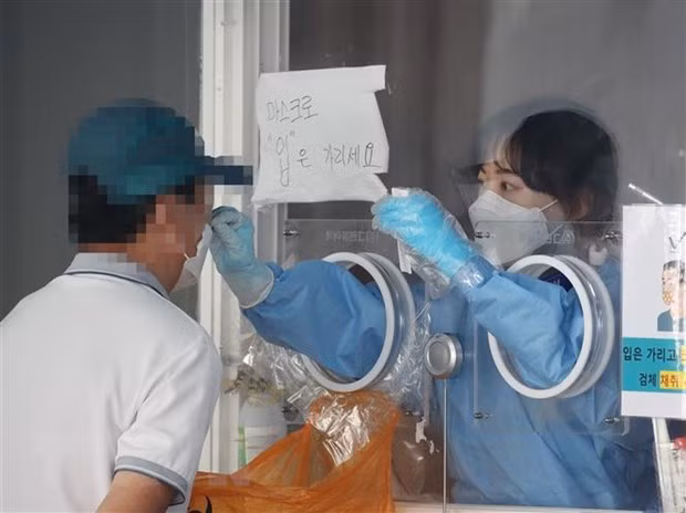 Nhân viên y tế lấy mẫu xét nghiệm COVID-19 cho người dân tại Hàn Quốc. Ảnh: Yonhap/TTXVN